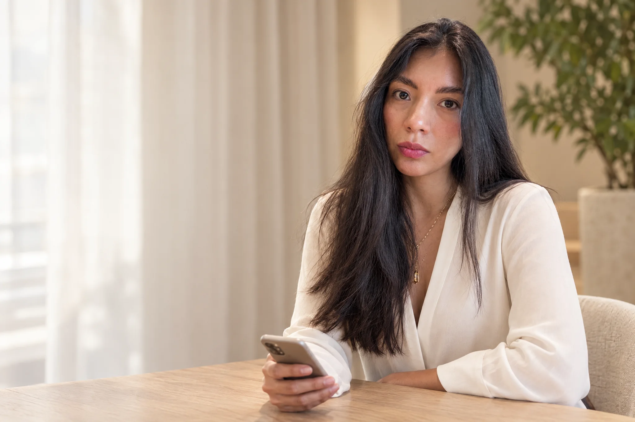 Nathalia Salazar, founder of YourAgentLab, at a table in Dubai with her phone in hand